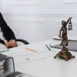 Top AI Tools for Lawyers and Legal Professionals to Save Time in 2026 A legal professional's workspace featuring Lady Justice statue, documents, and a laptop.