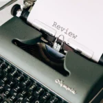 Writesonic vs Copy.ai: Which AI Writing Tool Is Better for Bloggers in 2026? Classic green typewriter with paper displaying 'Review', perfect for creative writing themes.
