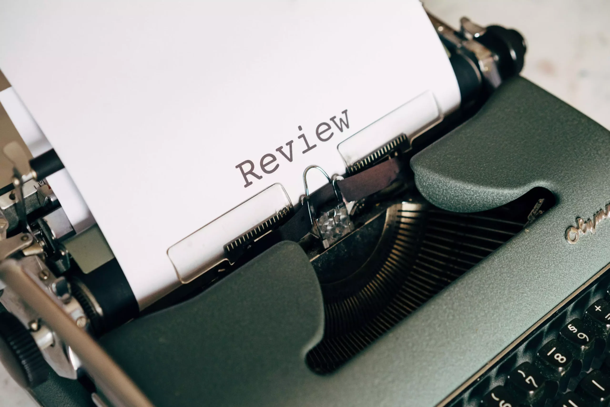 Close-up of an antique typewriter printing the word 'Review' on white paper.