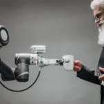 An elderly man receives a cup from a robotic arm in a modern office setting.