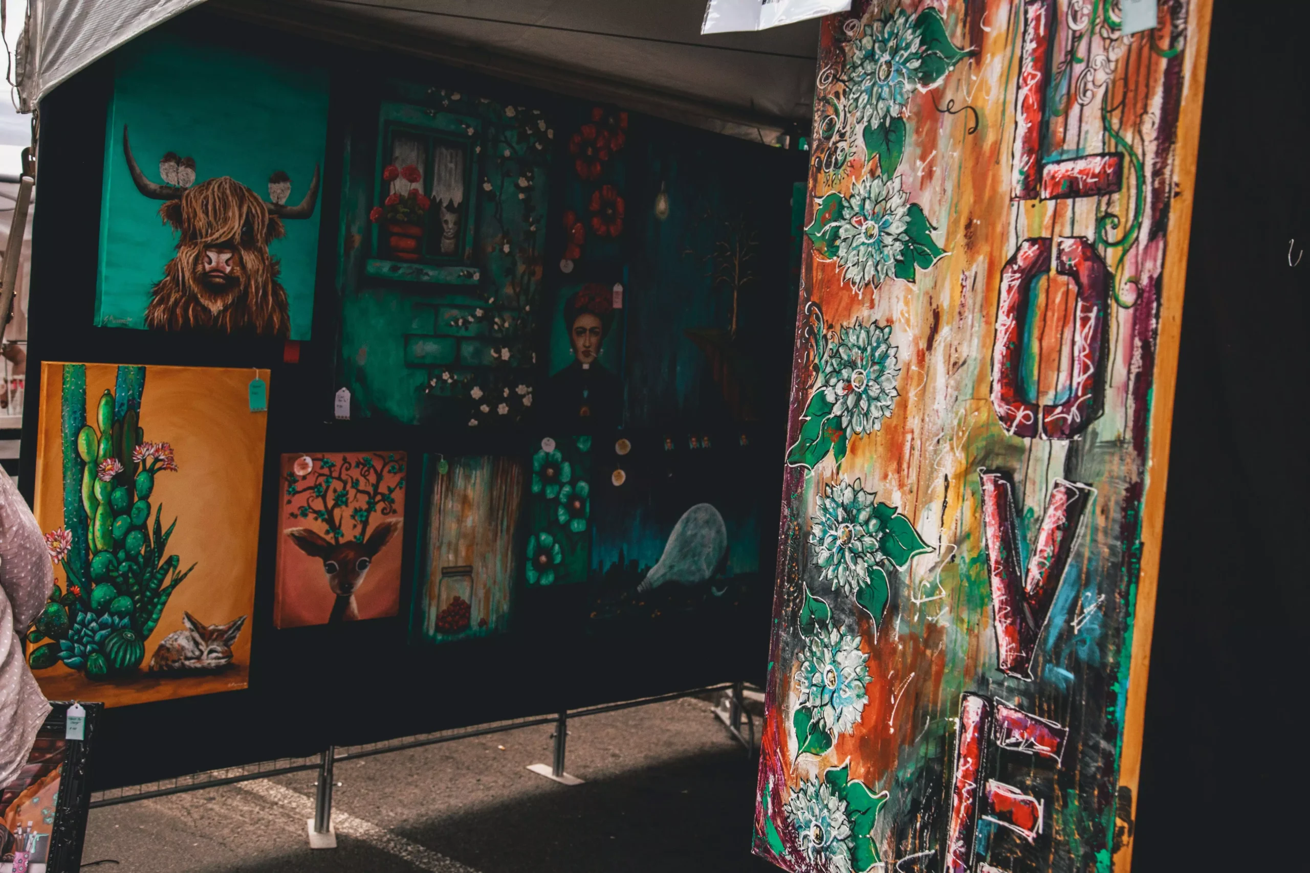 Colorful display of diverse artworks at an outdoor art fair highlighting contemporary styles.