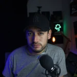 Male content creator in a home studio setup with microphone and soft lighting.